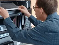 Appliance repair technician replacing a microwave vent filter in Peoria, IL