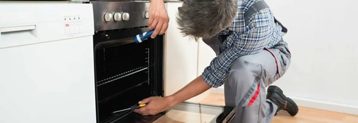 Oven repair technician inspecting and servicing an electric oven in Peoria, IL
