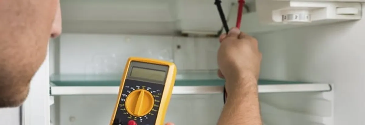Refrigerator repair technician testing electrical components with a multimeter in Peoria, IL
