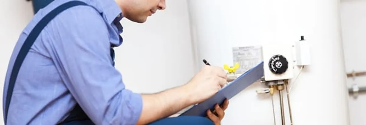 Water heater repair technician inspecting the unit and recording service notes in Peoria, IL
